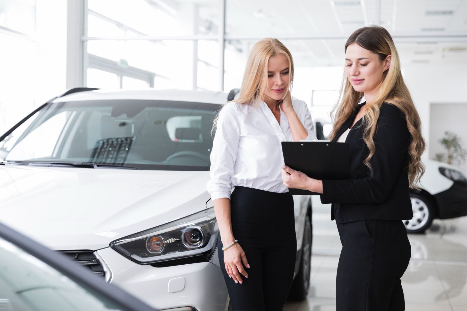 Saleswoman talking with a customer at a car dealership