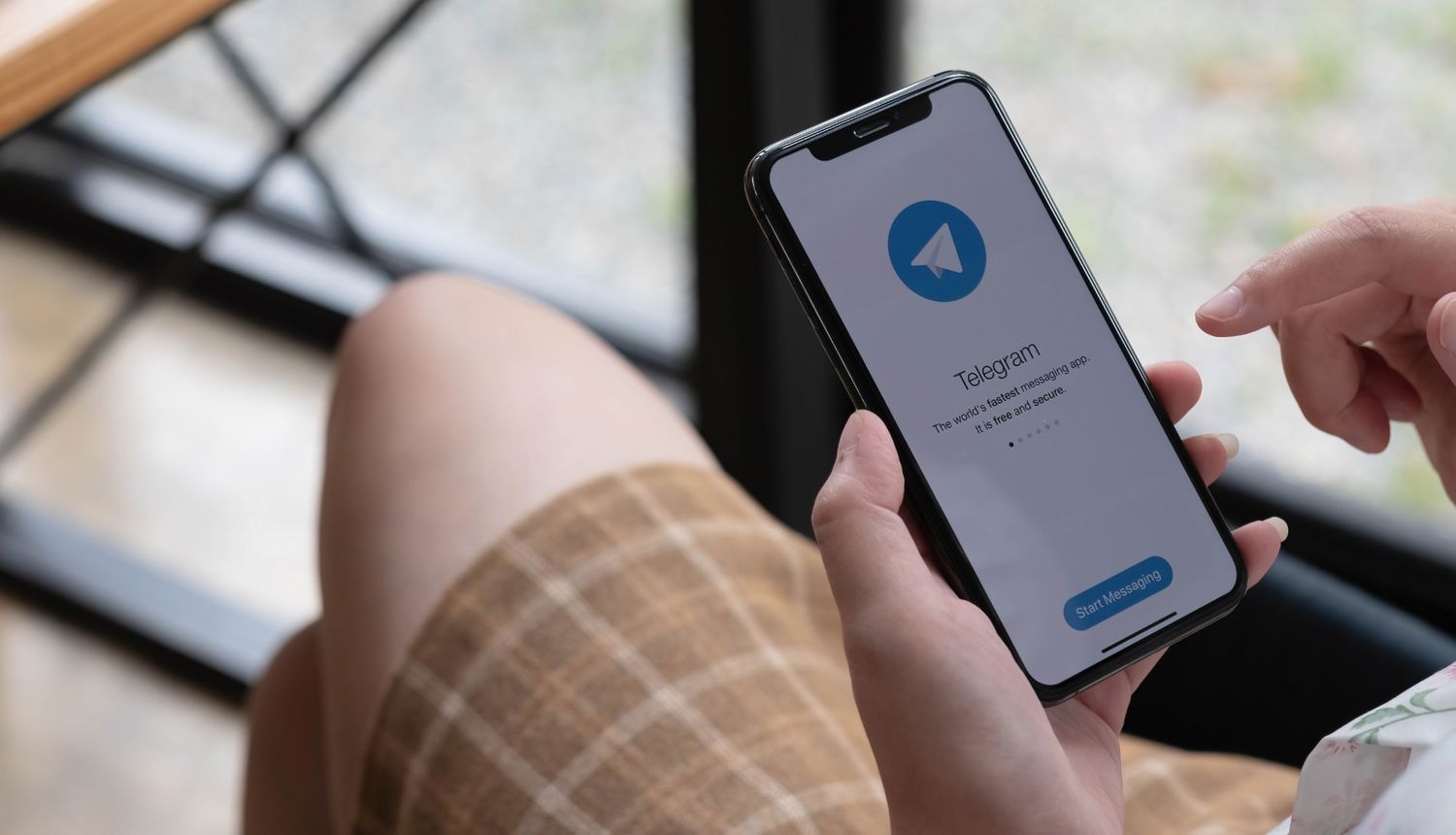 Woman holding phone with Telegram app